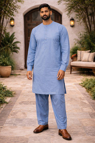 Man wearing a light blue shalwar kameez with pants in an outdoor setting.